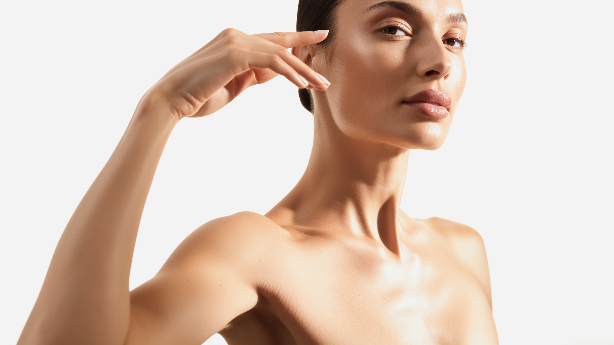 Nahaufnahme einer Frau mit makelloser Haut, die ihre Hand elegant neben das Gesicht hält vor weißem Hintergrund.